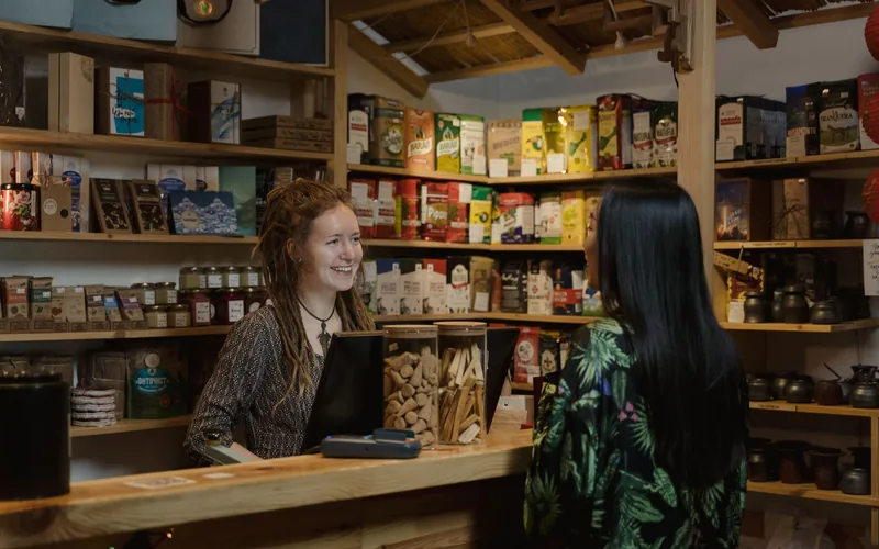 Comerciante atendiendo a una clienta en el mostrador de un local de barrio